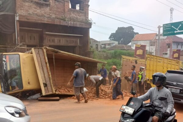 Truk Bermuatan Bata Merah Terguling di Kota Batu, Pagar Rumah Warga Hancur