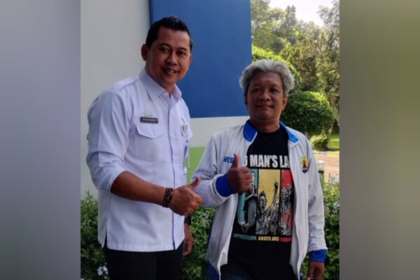 Priyo Sudibyo berbicara di depan kantor Perumda Tugu Tirta dengan latar belakang fasilitas lapangan sepak bola.