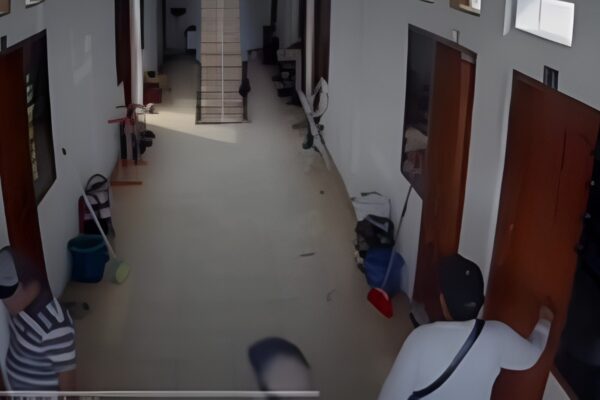 Tangkapan layar CCTV berwarna memperlihatkan beberapa orang berdiri di lorong kos.