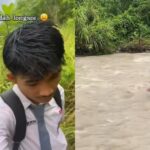 Asdar dengan seragam sekolah dan perlengkapan seadanya saat berjalan di jalanan berlumpur.